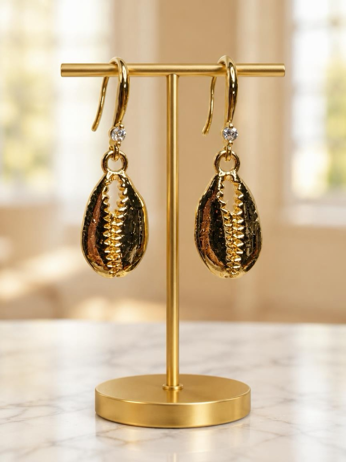 Golden Cowrie Shell Earrings – 18K Gold-PlatedDescriptionBring a touch of coastal elegance to your jewelry collection with these beautiful Golden Cowrie Shell Earrings.Featuring beautifully detailed cowrie shell charms with a polished 18K gold-plated fini