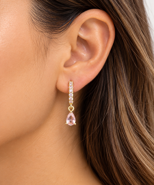 Title: Blush Pink Teardrop Huggie Earrings | 18K Gold-FilledDescriptionAdd a soft touch of elegance and sparkle to your jewelry collection with our Blush Pink Teardrop Huggie Earrings.Featuring delicate, sparkling pink cubic zirconia stones along the gold